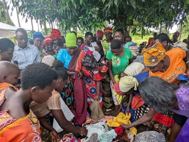 Women distributing donated clothing under a tree